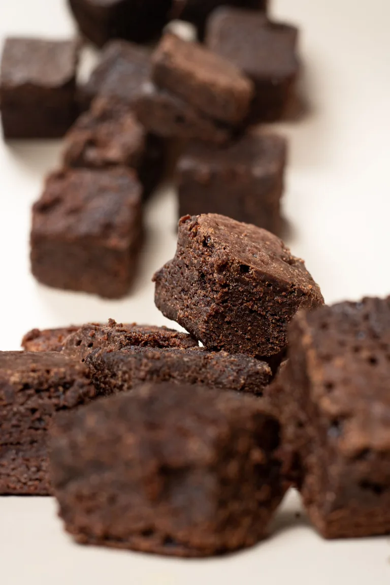 Chocolate brownie squares stacked to show their baked crumb and edges